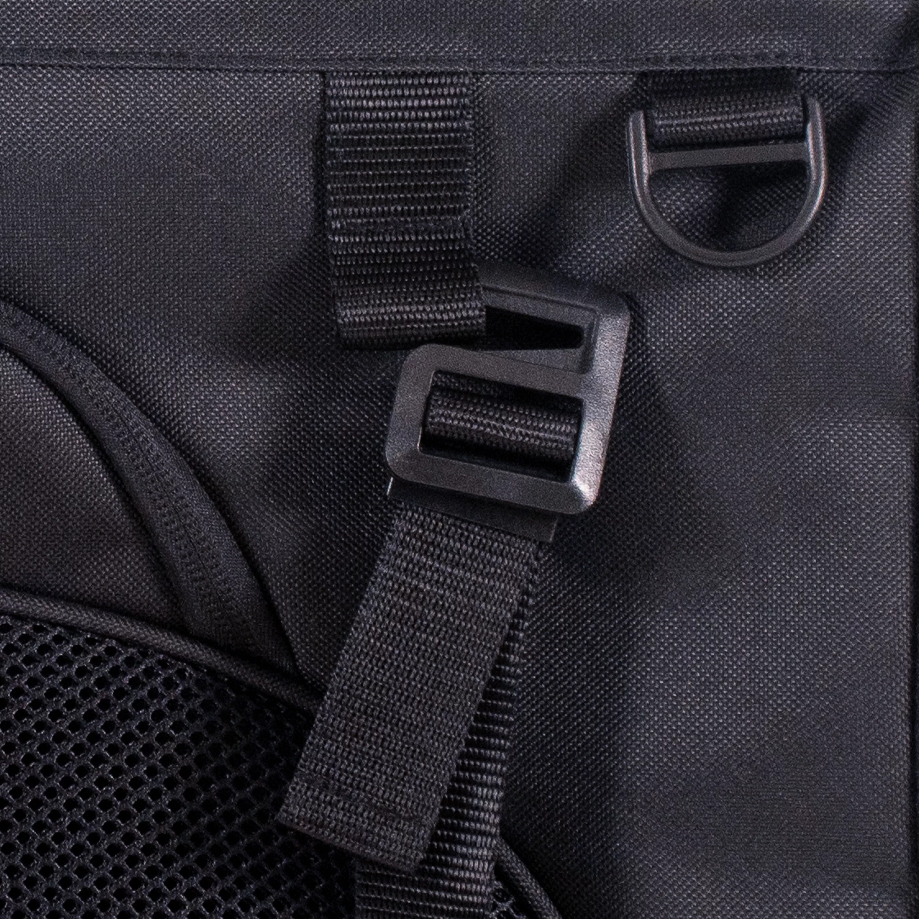 Close-up of a black g‑hook fastener attached to an adjustable webbing strap on the side of the pet carrier, with a D‑ring positioned above it and mesh fabric partially visible.
