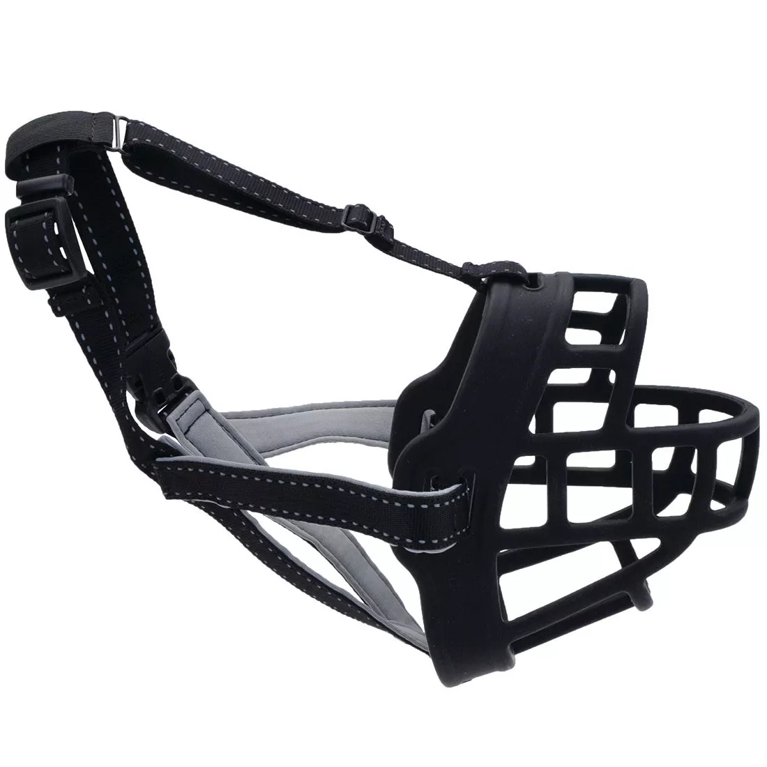 A product image of a soft basket muzzle displayed on a white background. The muzzle consists of a flexible black basket structure made from interlocking horizontal and vertical straps that form an open grid around the snout area. The muzzle includes a wide padded noseband in gray fabric, stitched to the basket frame. Two adjustable black nylon straps extend backward from the basket: one strap curves upward and includes a black plastic side‑release buckle for securing behind the dog’s head, while another strap extends horizontally along the side for fit adjustment. Additional black stitching reinforces the connections between the straps and basket.
