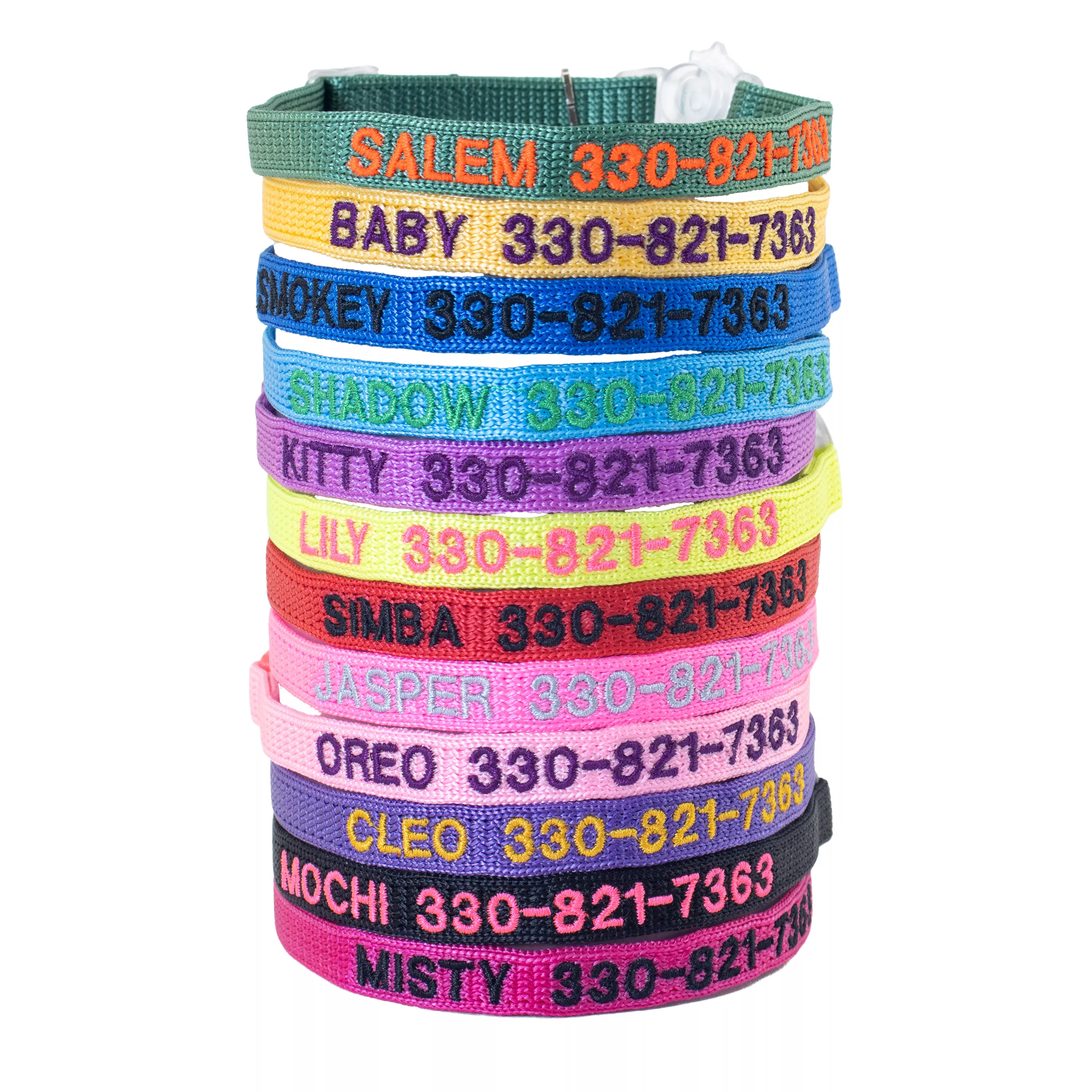 Stack of personalized cat collars in assorted colors, each embroidered with a pet name and phone number and secured with a clear plastic buckle.
