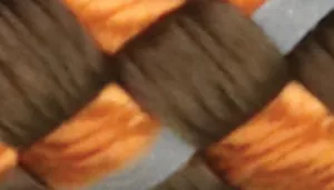 Woven pattern with dark brown strands crossed over orange and tan strands.
